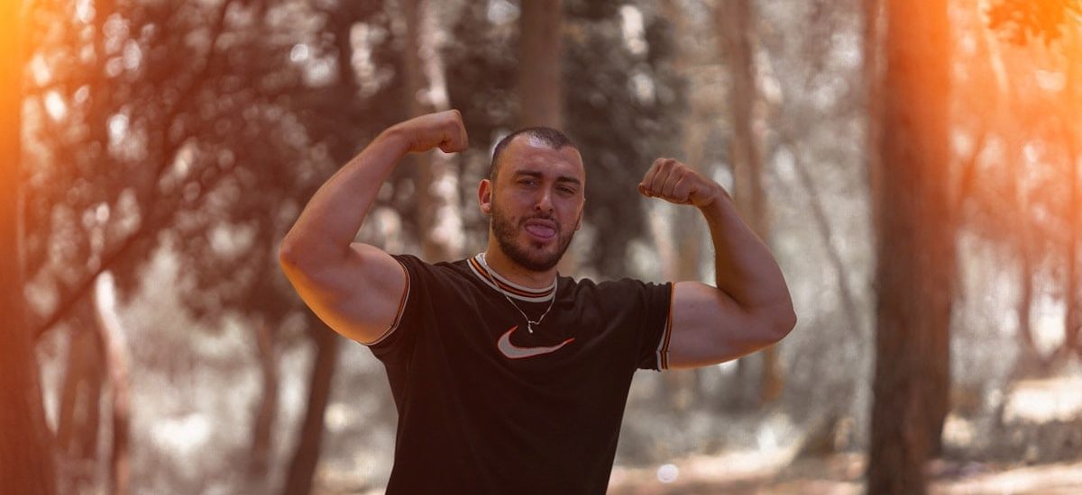 a man flexing his muscles in the woods